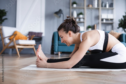 Wallpaper Mural Smiling woman doing stretching exercises in the living room at home. Torontodigital.ca
