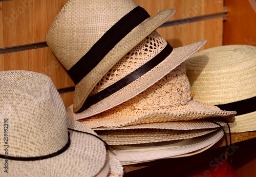 A group of hats from the sun on the shop window on the market. A set of men's straw hats with black ribbon. Cropped shot, horizontal, close-up, no one. Fashion concept.