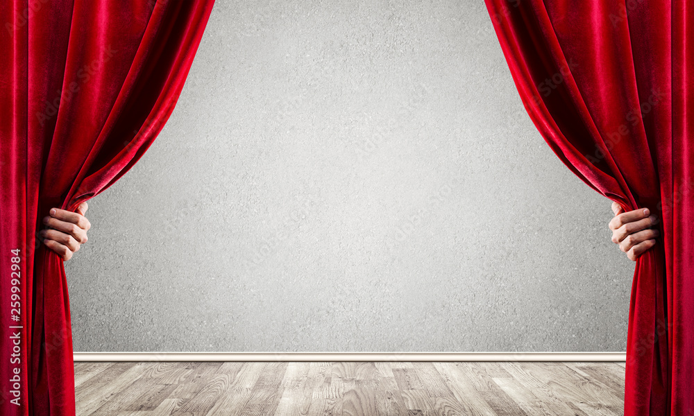 Concrete wall behind drapery curtain and hand opening it