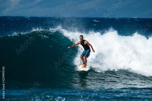 MAUI / USA - 14 DECEMBER 2018: Hawaiian adult surfer rides the ocean wave with smile and happy face. Honolua surf spot on the north of Maui