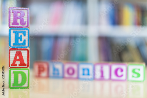 Alphabet blocks spelling the words read and phonics in front of a bookshelf photo