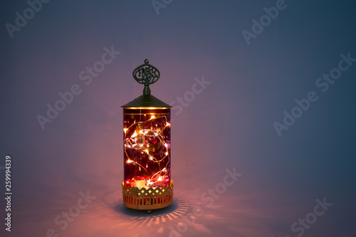 Ornamental Arabic lantern with burning candle glowing at night and glittering shadows. Festive greeting card, invitation for Muslim holy month Ramadan Kareem. Dark background