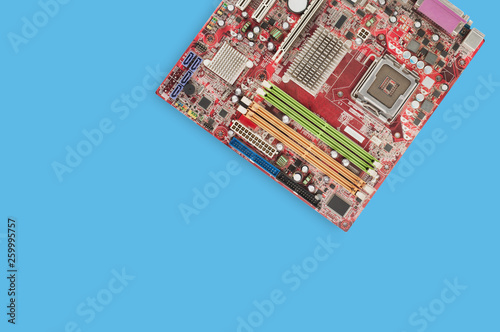 One red square motherboard for computer with electronics component on blue table. Top view. Computer repair concept. Copy space for your text