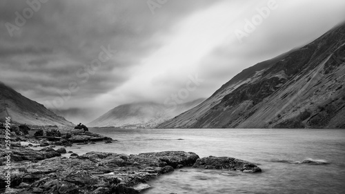 Stunning long exposure landscape image of Wast Water in UK Lake District during moody Spring evening in black and white