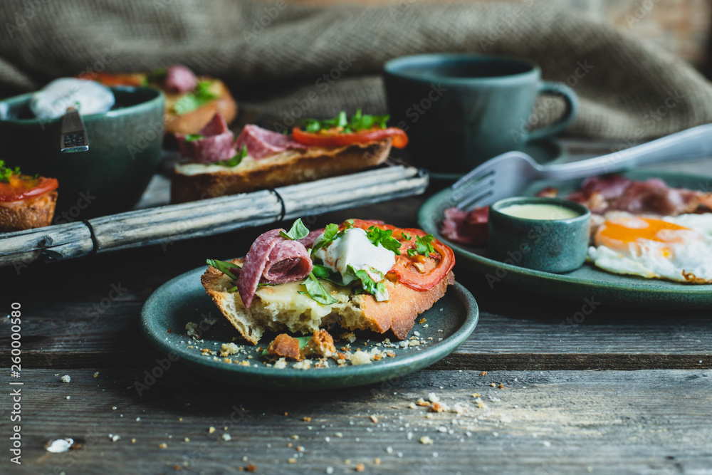 rustic breakfast, baked with basil, tomato, salami and cheese slices of bread, fried egg and bacon