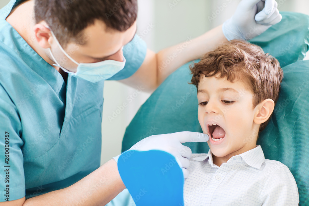 Fototapeta premium Boy child and dentist are checking teeth in the mirror.