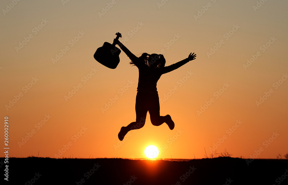 Silhouette of a guitar player at sunset, girl guitarist, silhouette of a guitar, music, girl jumping with a guitar Silhouette of a guitar player at sunset, girl guitarist, silhouette of a guitar, music, girl jumping with a guitar