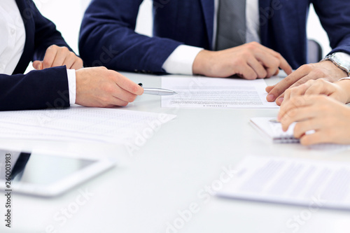 Group of business people and lawyers discussing contract papers sitting at the table, close-up. Successful teamwork, cooperation and agreement concepts