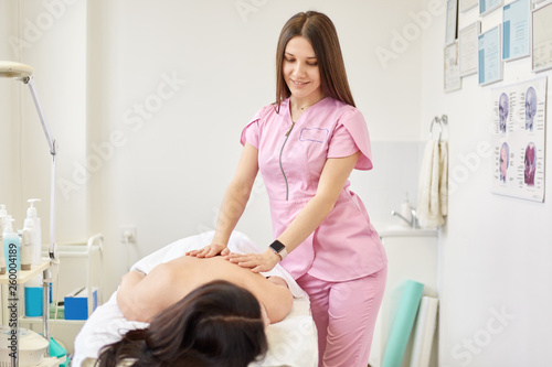 Beautiful young woman relaxing from massage on comfortable couh at beauty salon  attractive woman has body care procedures in cosmetological clinic  takes care of her health  enjoys of visiting spa.