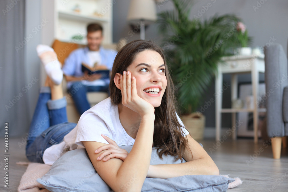 Portrait of attractive woman relaxing on floor with blurred man in background. Portrait of attractive woman relaxing on floor with blurred man in background.