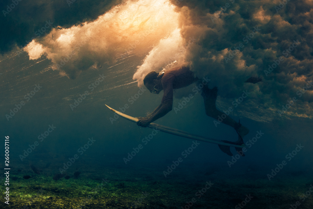 Surfer dives under the breaking wave