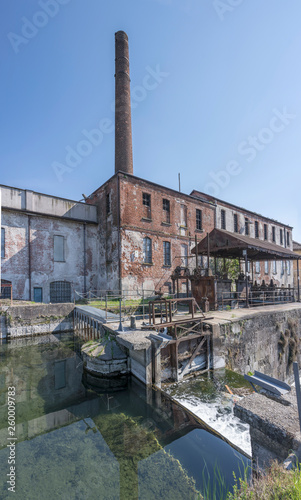 old chimney with industrial buildings and millwork of lock on Naviglio canal, Milan, Italy