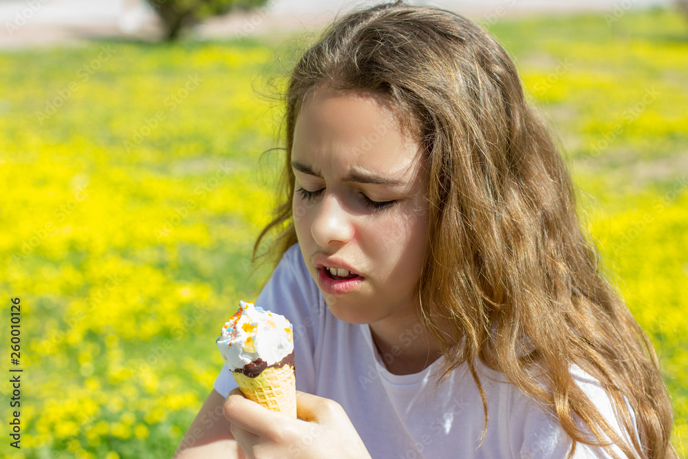 Dissatisfied unhappy teen girl eats tasteless ice cream in a waffle cone in summer. Selective focus Dissatisfied unhappy teen girl eats tasteless ice cream in a waffle cone in summer. Selective focus