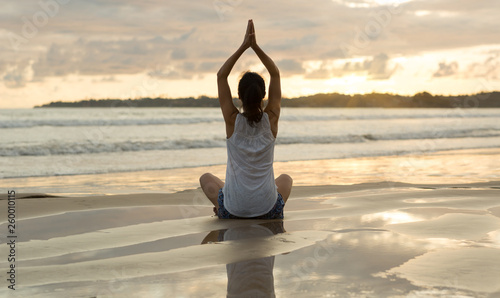 Meditating yoga woman sit at the seaside beach