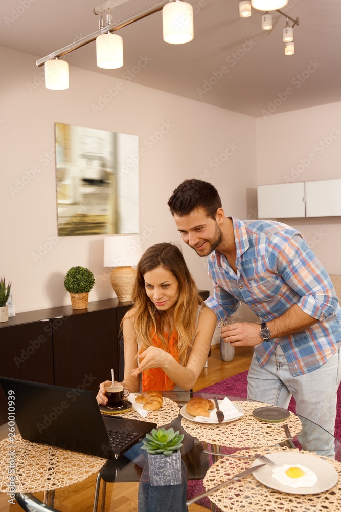Young couple having breakfast and using internet