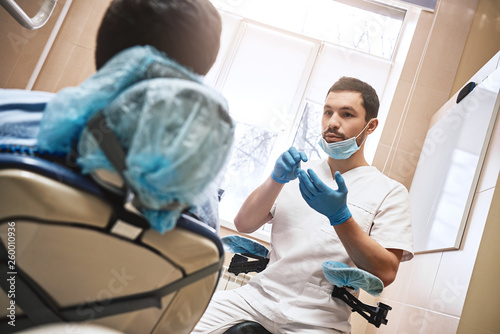 Dental excellence. Dentist discusses with the patient the state of his teeth in modern dental clinic