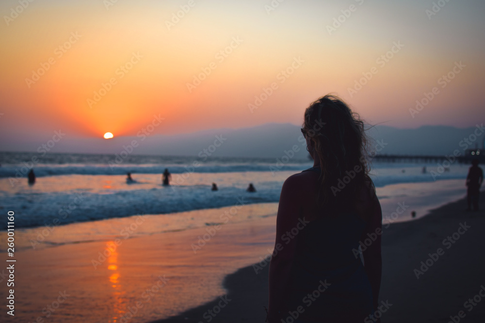 Woman at sunset at the beach or ocean. Summer landscape California. Santa Monica Beach.