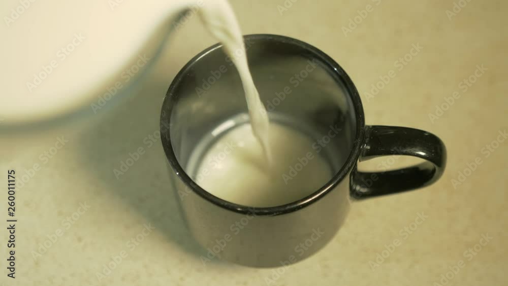 Slow Motion Overhead Shot of Steaming Hot Milk Being Poured into a Black Mug. Slow Motion Overhead Shot of Steaming Hot Milk Being Poured into a Black Mug.