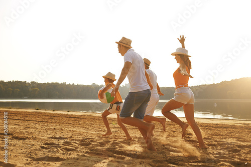 Happy family playing on the beach at sunset