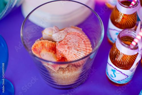 Glass vase with sweet brown sugar sand and difftent seashells. Seatime theme on the party's candybar photo