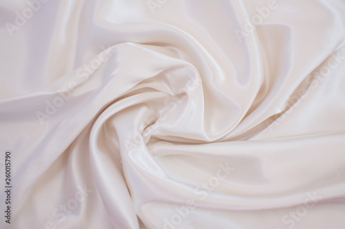 Silk wrinkled white fabric. View from above. Textile and texture concept - close up of crumpled silk white wavy fabric background
