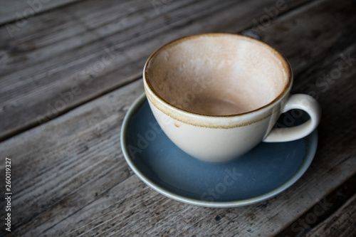 Empty cup of coffee in earthern ware cup with saucer on rustic wooden table photo
