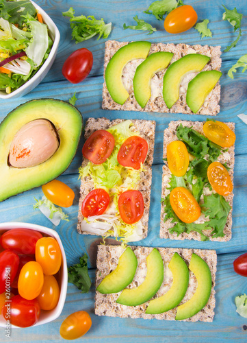 Healthy snack from wholegrain rye crispbread cracker with cherry tomatoes, avocado and salad. Proper nutrition.
