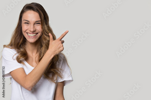 Laughing woman pose over white grey background pointing at copyspace