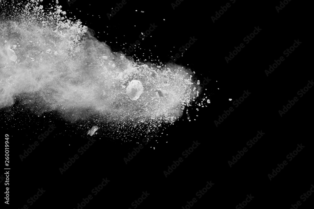 Freeze motion explosion of white powder on a black background.Stopping the movement of white dust on dark background.