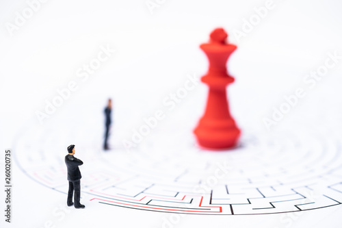 Miniature people, businessman and chess pieces in the labyrinth or maze figuring out the way out. Business concept, finding solution, strategic, and business opportunity.