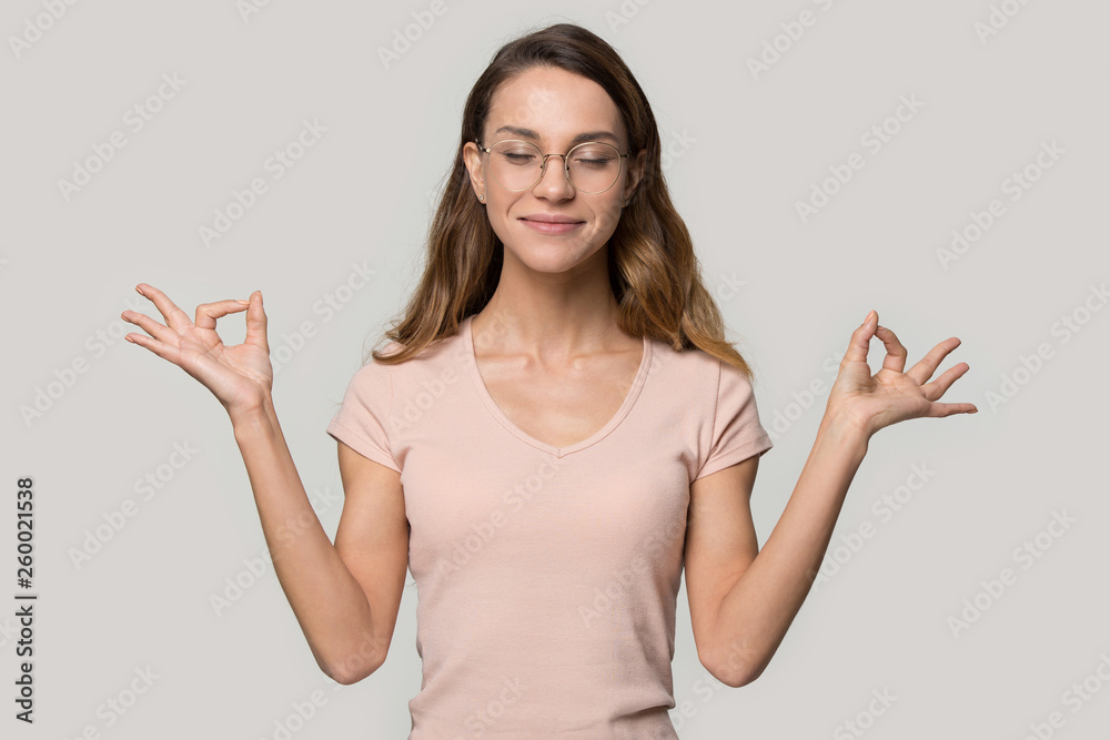 Smiling woman closed eyes doing yoga over grey background Smiling woman closed eyes doing yoga over grey background