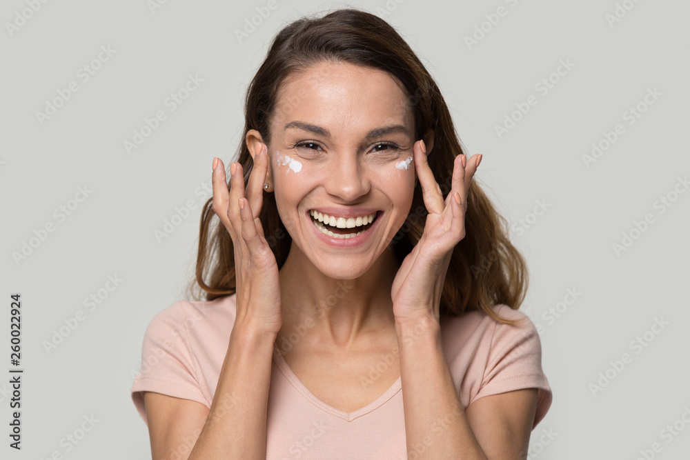 Happy woman looking at camera applying eyelid moisturizing cream Happy woman looking at camera applying eyelid moisturizing cream