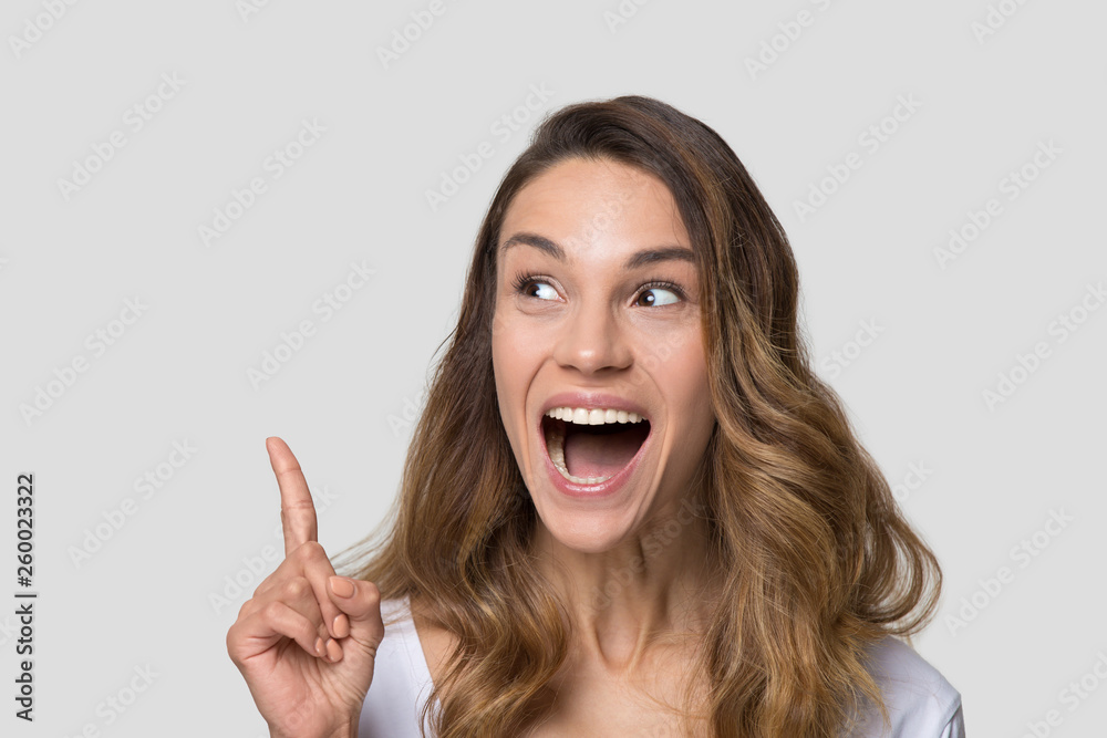 Astonished millennial woman pointing finger above on copy space. Astonished millennial woman pointing finger above on copy space.