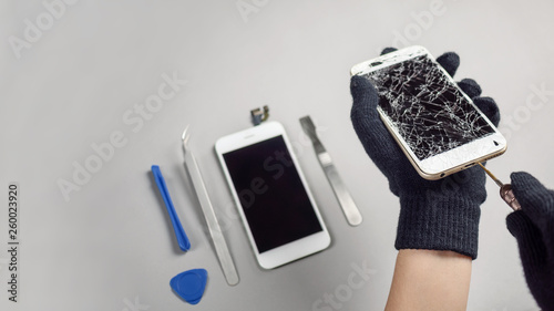 Technician or engineer opening broken smartphone for repair or replace new part on desk with copy space