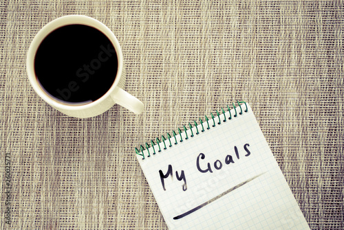 Writing down goals. A notebook for goals and a cup of coffee. Goals concept