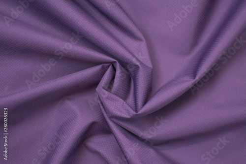 Silk crumpled fabric purple. View from above. Textile and texture concept - close up of crumpled silk violet wavy fabric background