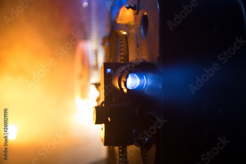 Old vintage movie projector on a dark background with fog and light. Concept of film-making.