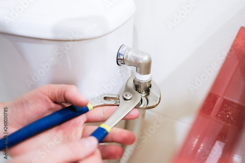 Sanitary worker performs repair of toilet bowl. To repair the pipe from the toilet