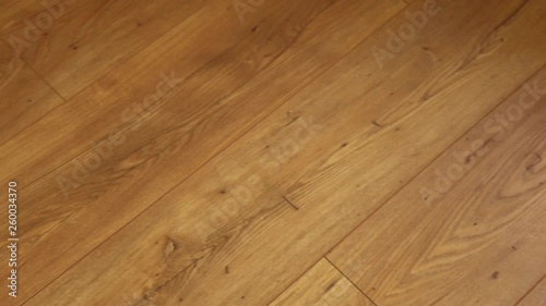 The camera moves along the floor, covered with laminated parquet with a brown wooden texture photo