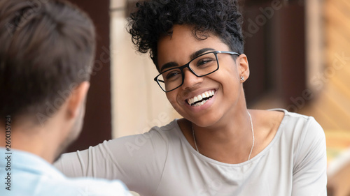 Happy african woman and caucasian boyfriend laugh on first date