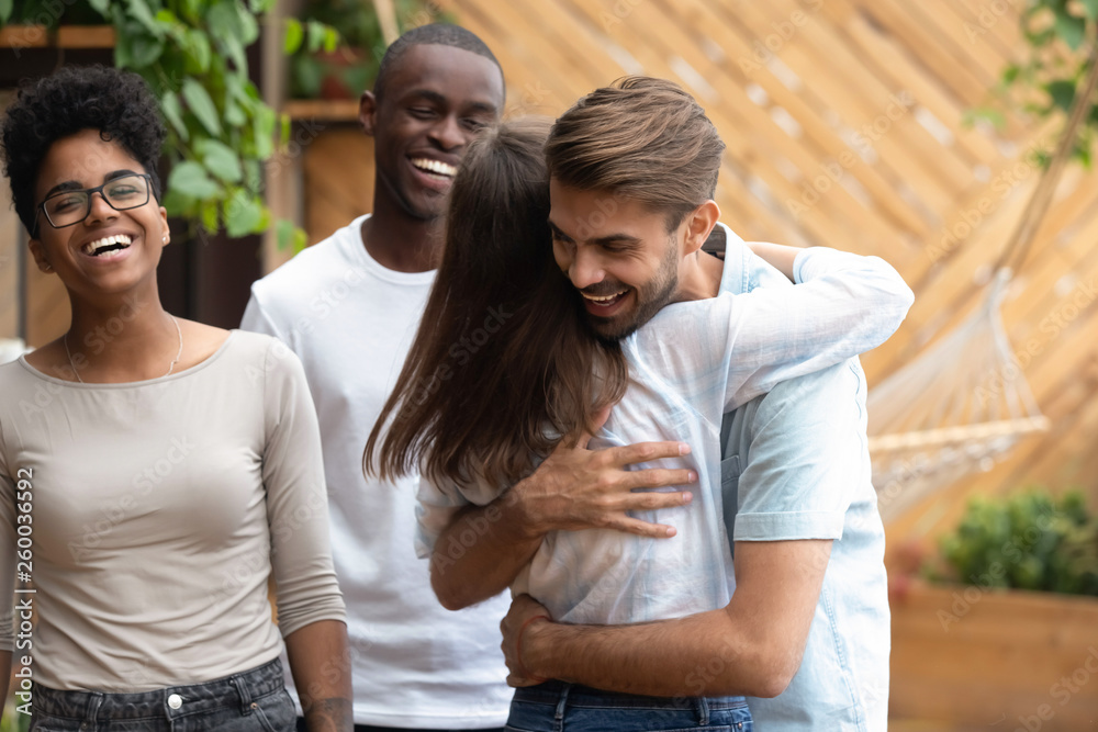 Happy man and woman greeting hugging at multi-ethnic friends meeting Happy man and woman greeting hugging at multi-ethnic friends meeting