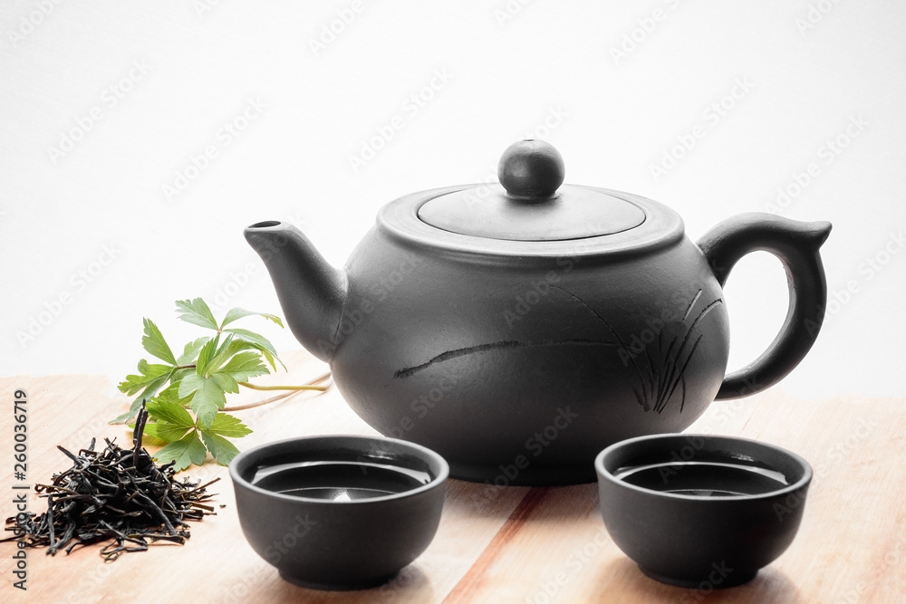 Set for tea ceremony. Large clay  teapot, fresh green tea and cups. Front view. Copy space, space for text, isolated.