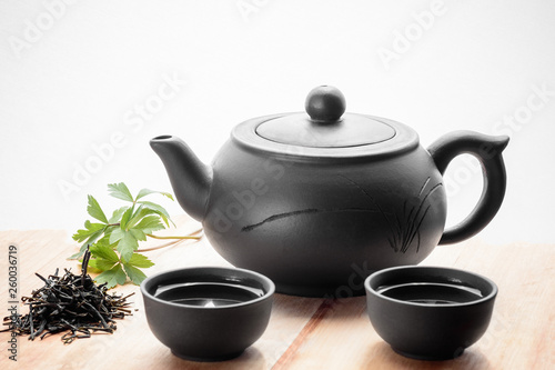 Set for tea ceremony. Large clay teapot, fresh green tea and cups. Front view. Copy space, space for text, isolated.
