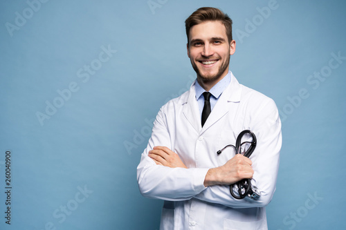 Portrait of confident young medical doctor on blue background.