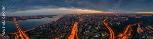Night Voronezh city panorama from above, aerial view of city after sunset with illuminated roads and traffic, buildings, river and bridges, drone photo