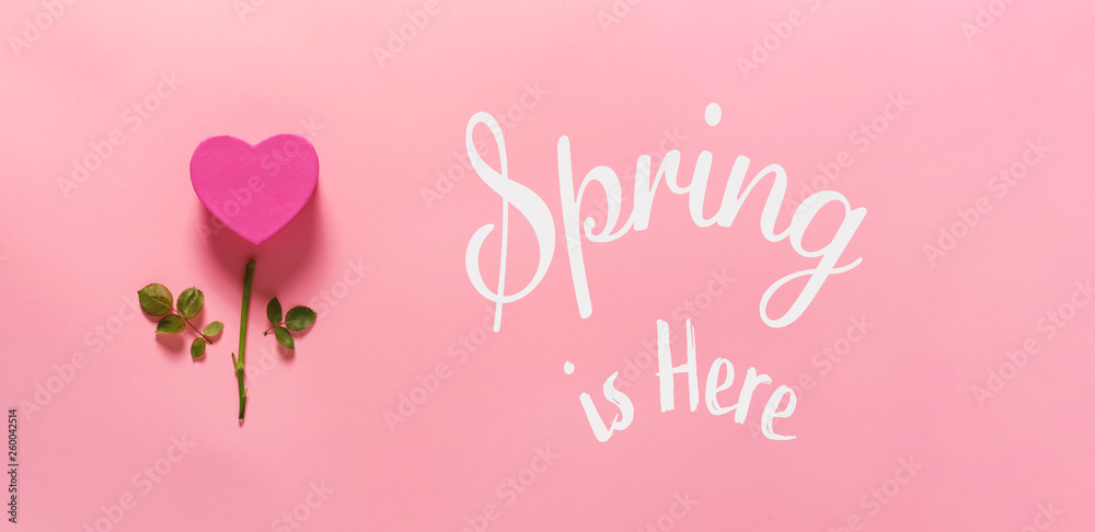 Spring is here message with heart flower top view flat lay Spring is here message with heart flower top view flat lay