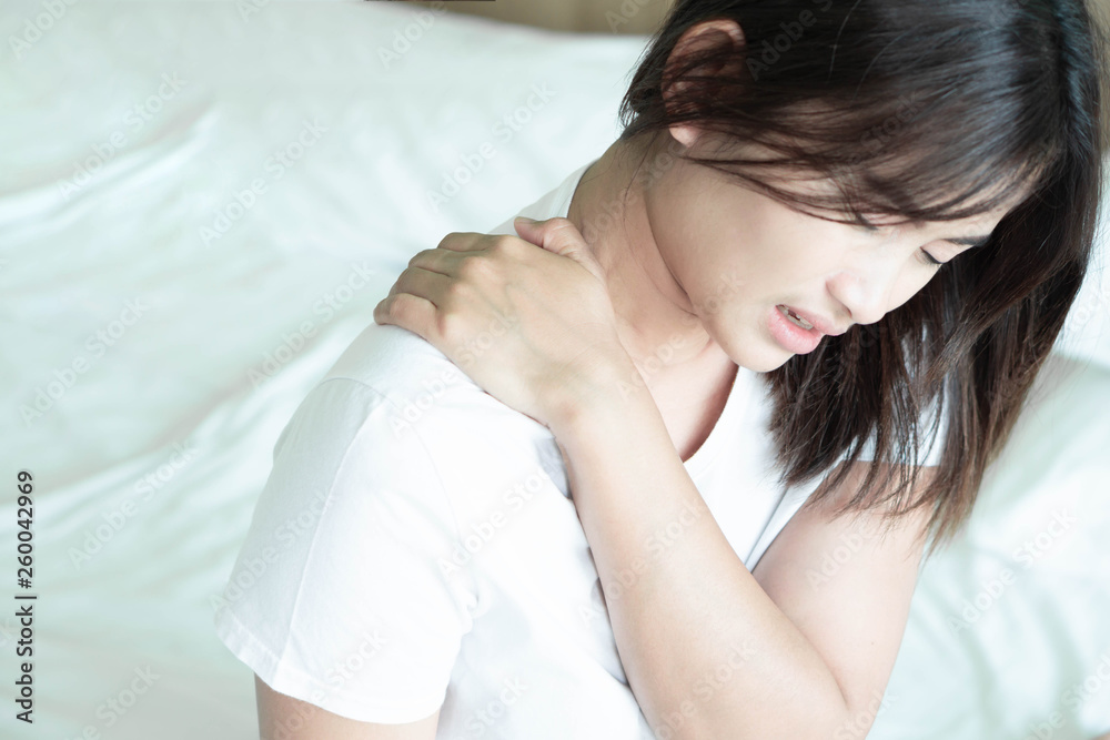 Closeup woman hand holding shoulder with pain on bed, health care and medical concept Closeup woman hand holding shoulder with pain on bed, health care and medical concept