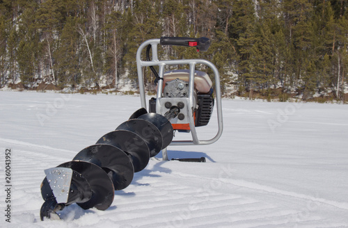 Motor drill for fishing in the snow. Portable drilling rig that is controlled by human physical strength. photo