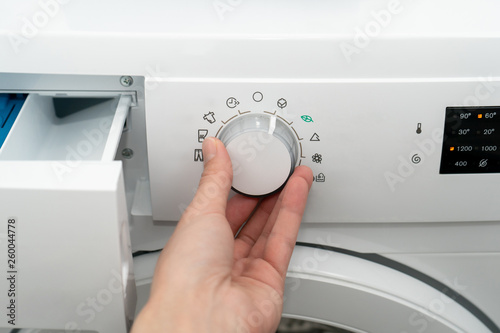 Female chooses the cotton mode in an automatic washing machine. Front view