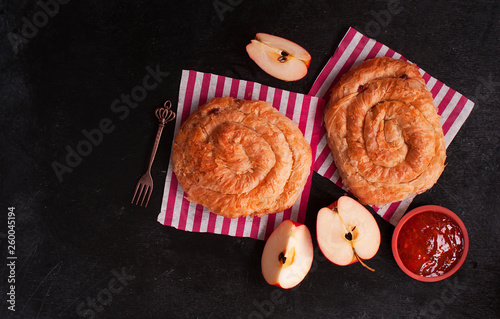 Apple pie in the shape of a snail and Apple jam on a black wooden table. The view from the top. Turkish and middle Eastern cuisine. Copy space.